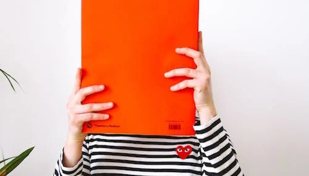 Woman reading with face covered by a book